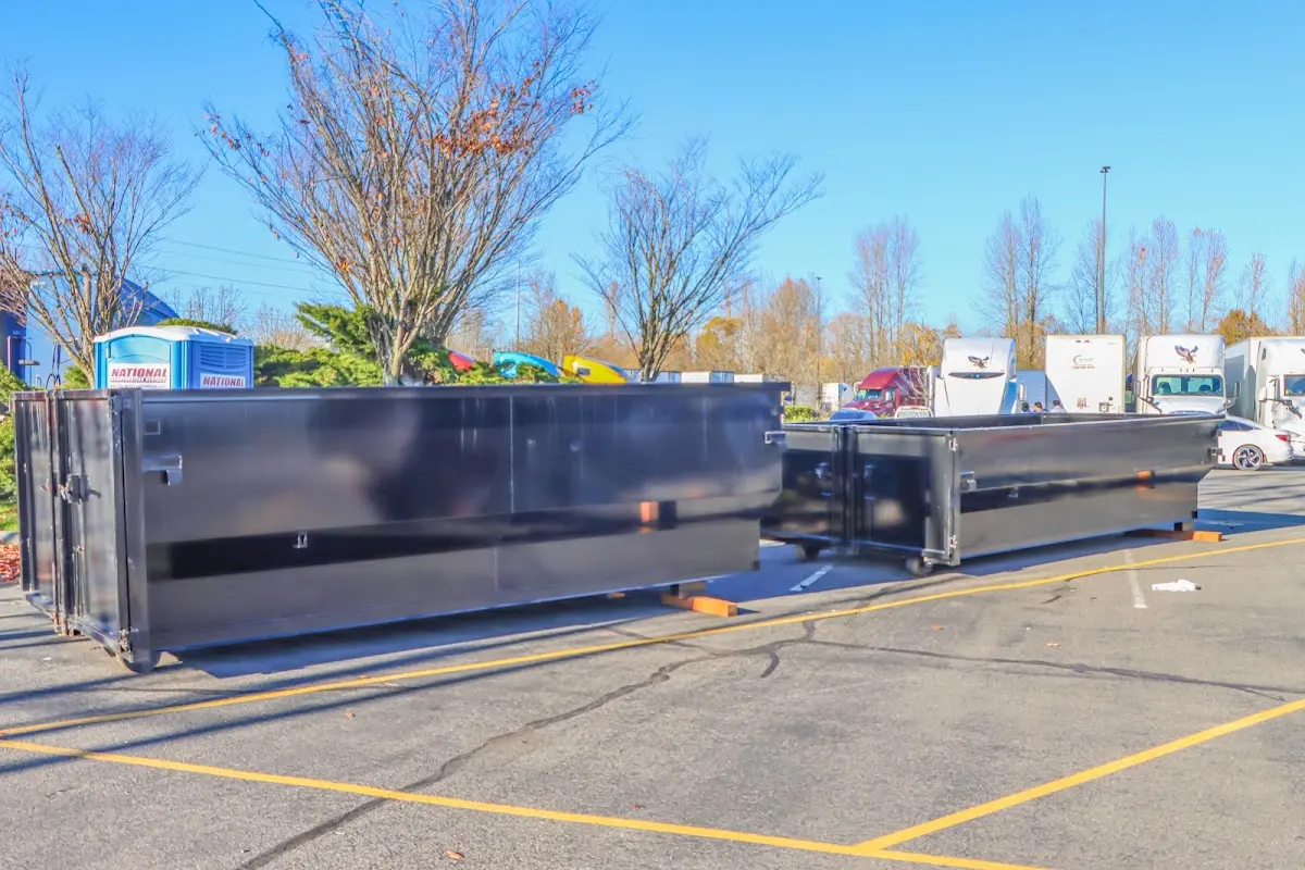 Professional dumpster rental service with roll-off container on residential driveway in August